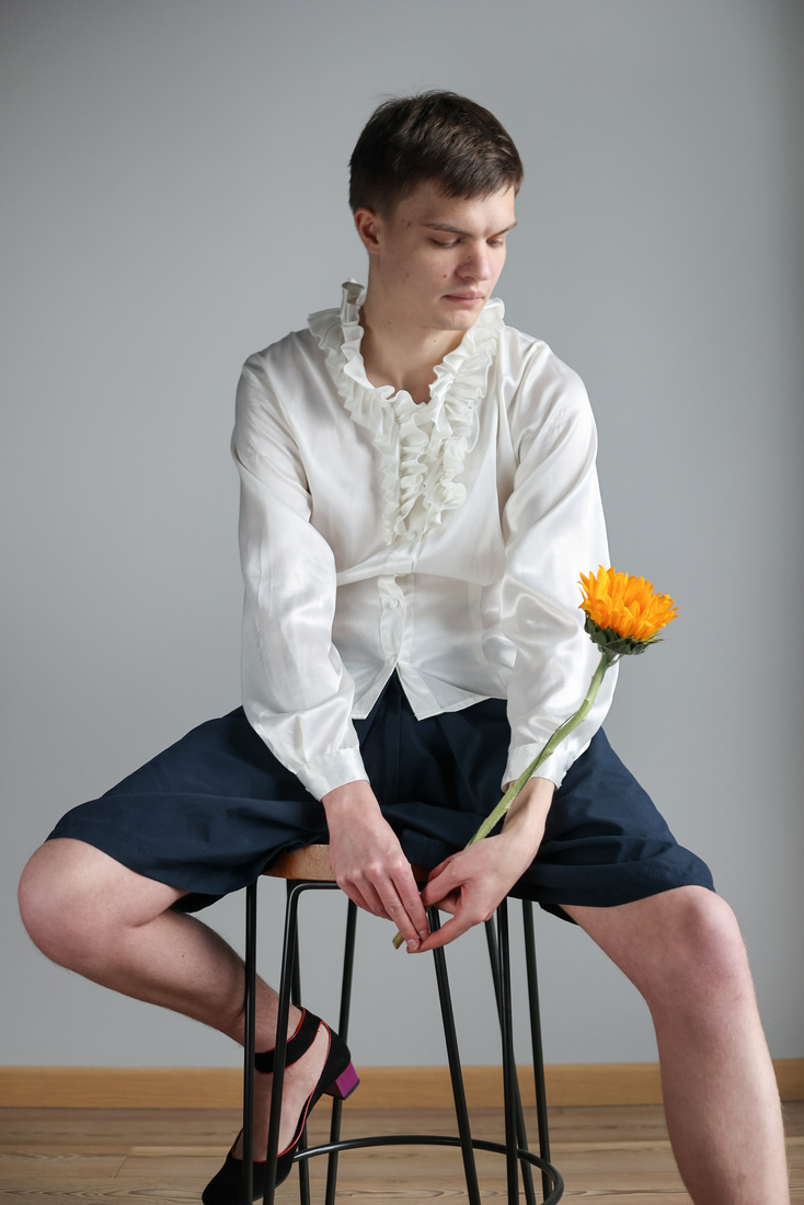 Man in Frilly Blouse, Shorts and Heels Holding Flower